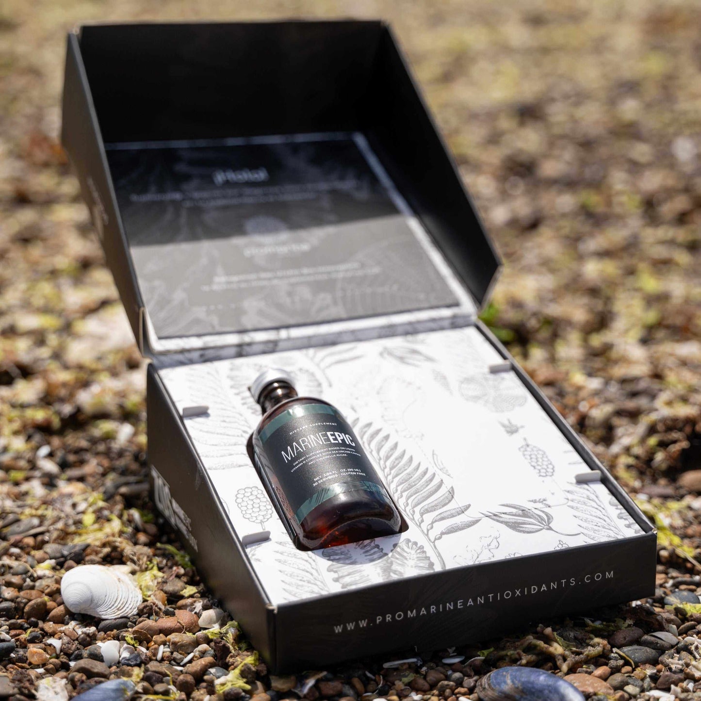 Bottle of Marine Epic biotechnology supplement for longevity and biohacking displayed in an open branded box on a natural ground background