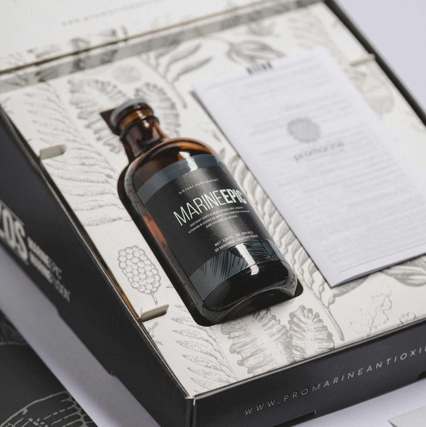 Bottle of Marine Epic biotechnology supplement for longevity and biohacking inside an open product box with informational booklet